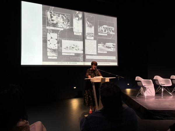 Stephanie Pilat presenting slides at a podium.