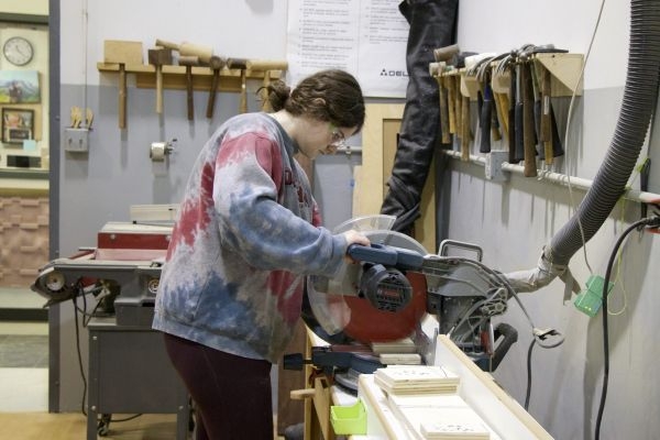 An interior design student uses a table saw in the Creating Making Lab.