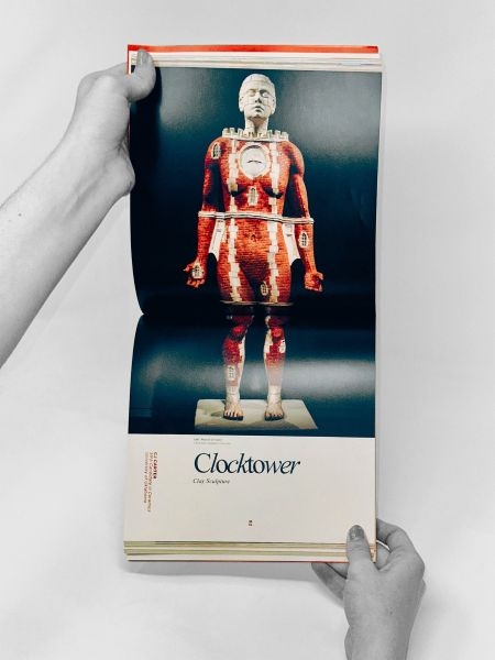 A clay sculpture by C J Carter titled "Clocktower" resembling a woman fused with a brick structure.