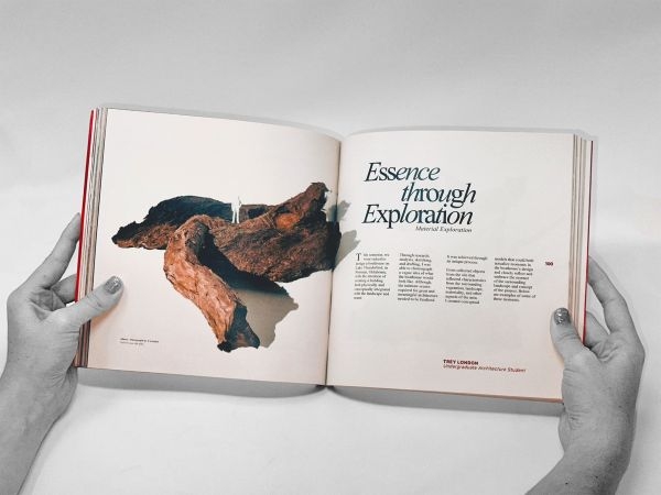 Hands opening the Telesis journal to the article "Essence through Exploration: Material Exploration" by Trey London.