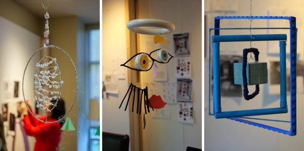 Three mobiles; the first is two concentric circles with lines of beaded wire in the center, the second resembles a face, and the third is a series of rectangles with a cube in the center.