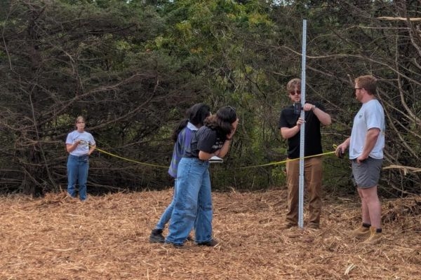 Students taking measurements outdoors.