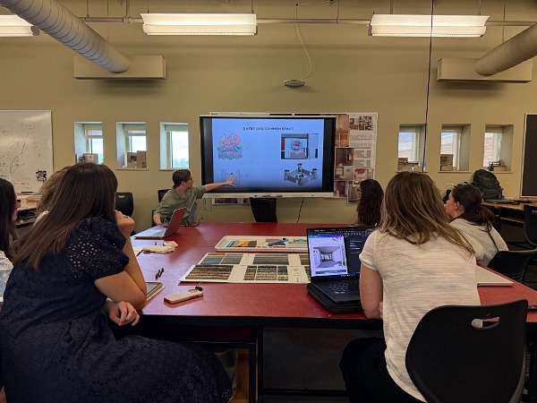Students at desks watching a video presentation. 