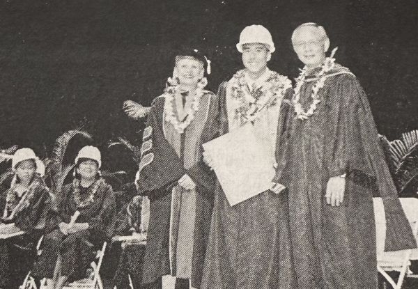 3 men on stage at graduation. 