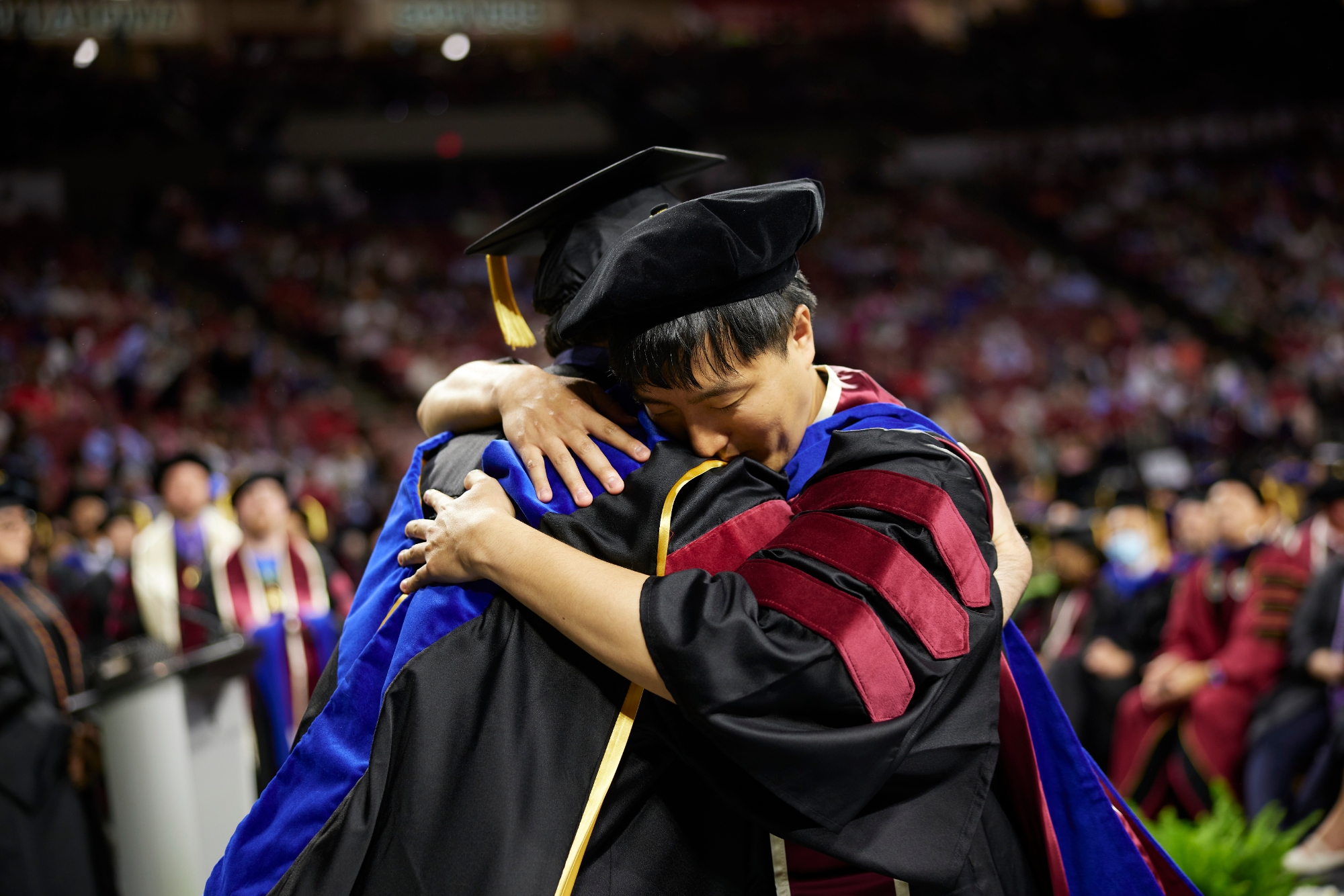 Two graduates hug. 