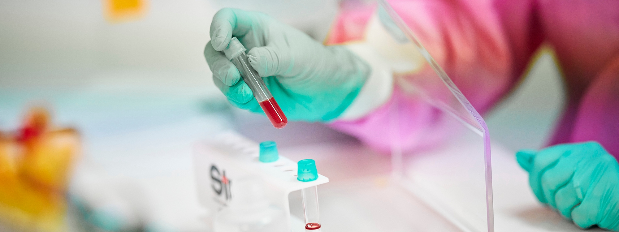 Lab technician holding vial with red liquid
