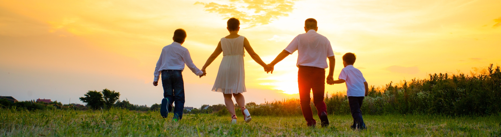 Family of 4 holding hands, running toward the sunset