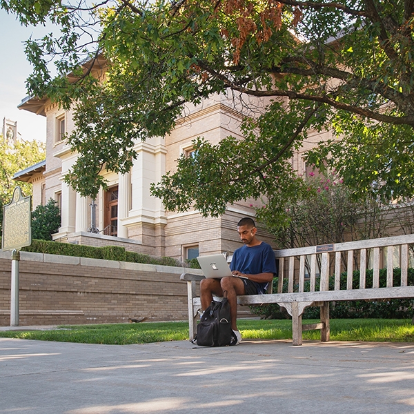 Student studying outside on a bench.