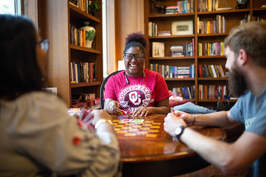 Three students sitting at a table playing a card game