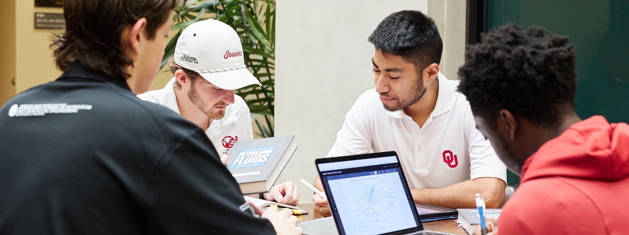 Group of 4 male students sitting at a table studying