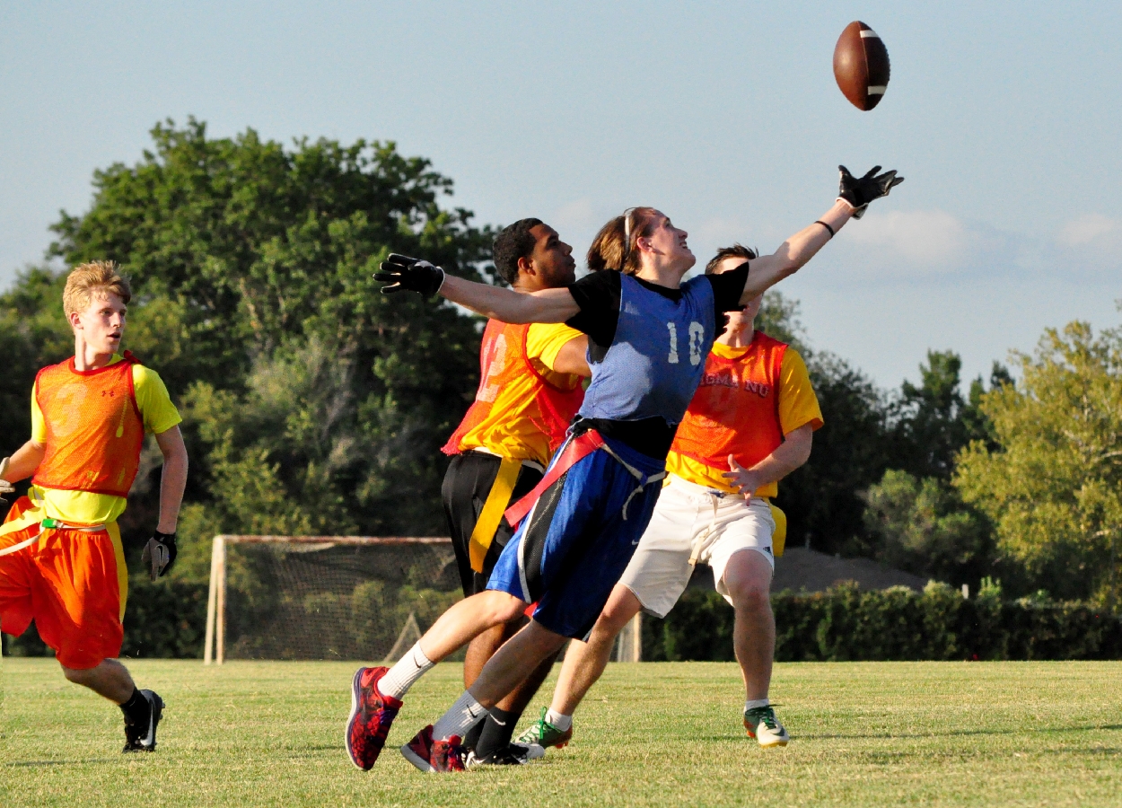Student reaches up to catch a football during an Intramurals game