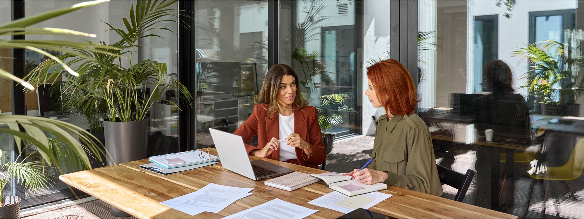 Two women sitting at a desk next to each other in front of a laptop computer
