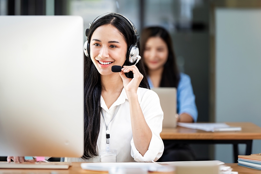 A person sitting at a desk, wearing a headset and working on a computer.