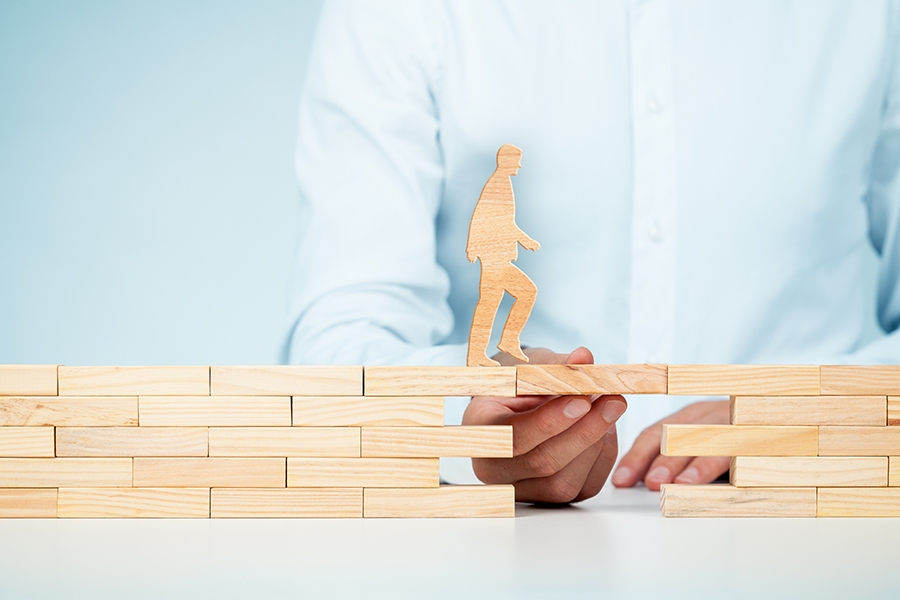 Wooden blocks forming a rudimentary bridge with a wooden cutout of a man crossing it.