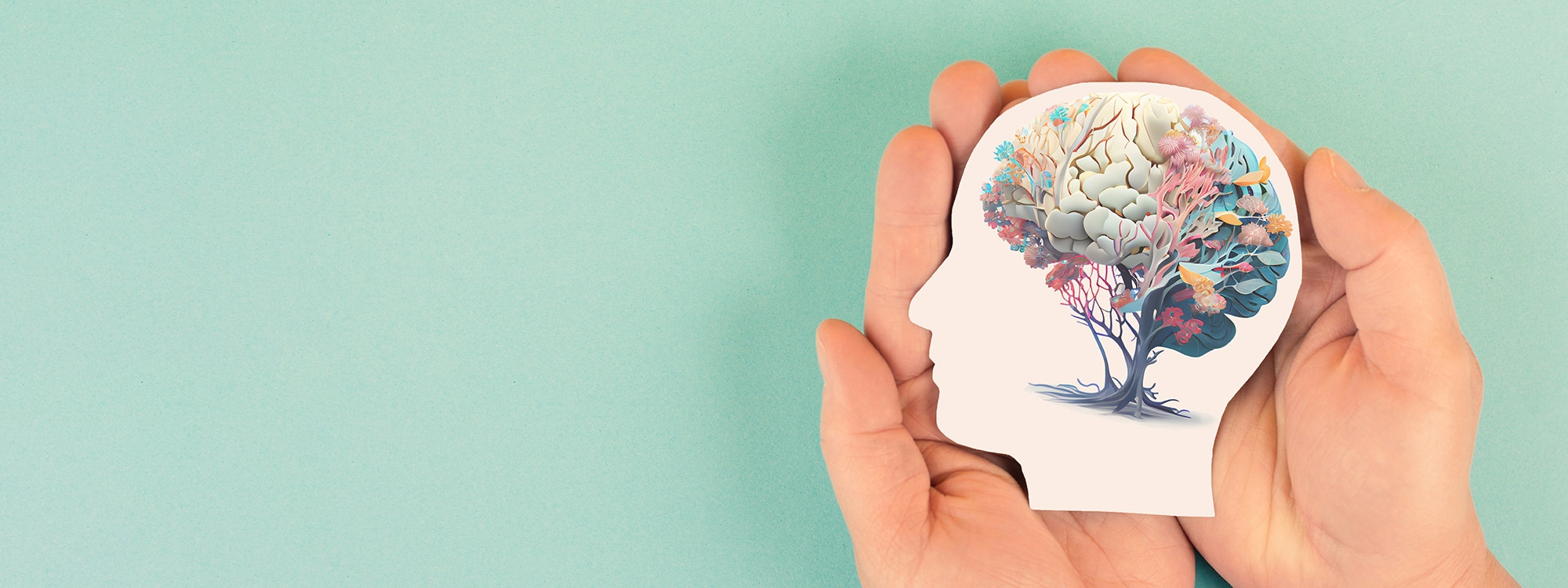 A pair of hands holding an object in the shape of a person's head, with the brain being represented by a tree,