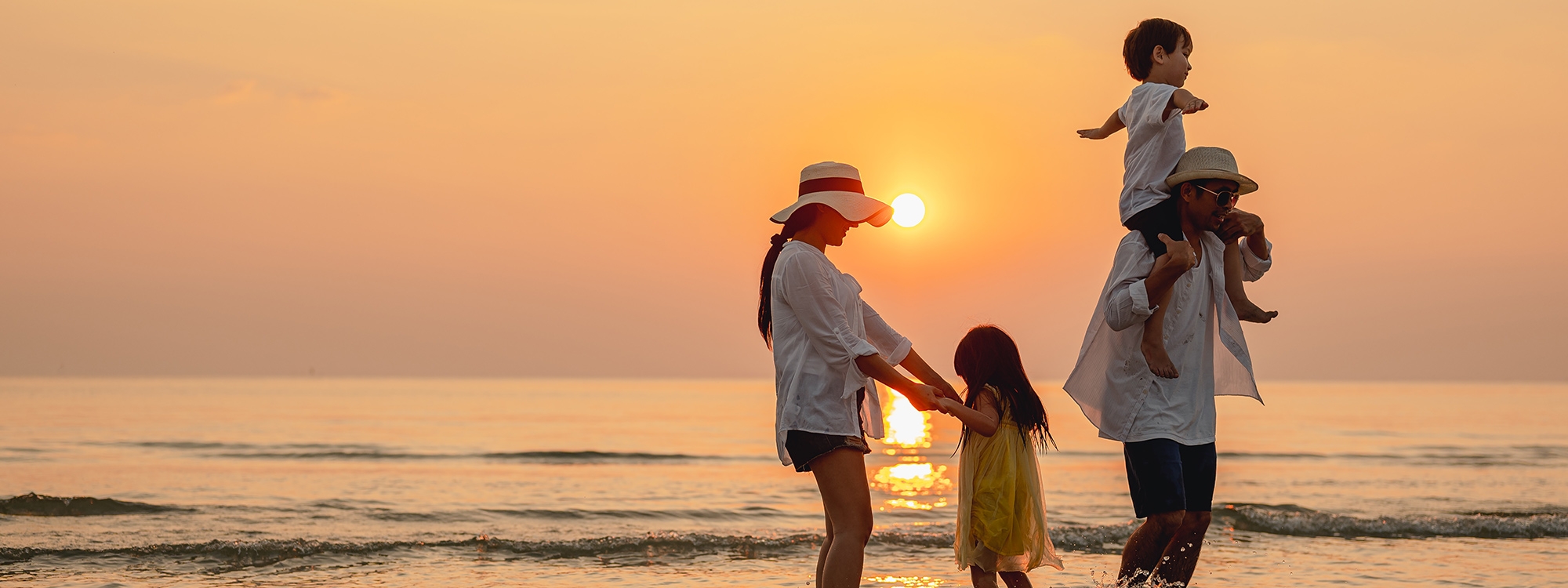 A family enjoying the beach during sunset.