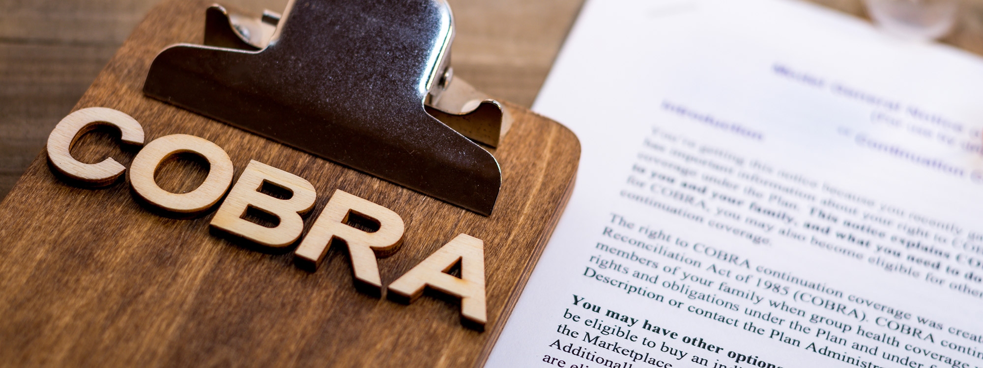 Clipboard with the word COBRA in wooden letters on top of it.