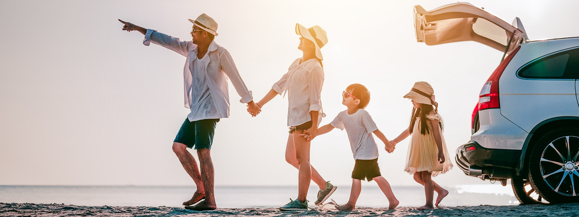 A family walking past the trunk of their card and pointing to what they're walking towards.