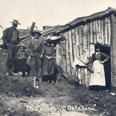 Picture titled "Mansion in Oklahoma" showing Black people standing in front of little house.