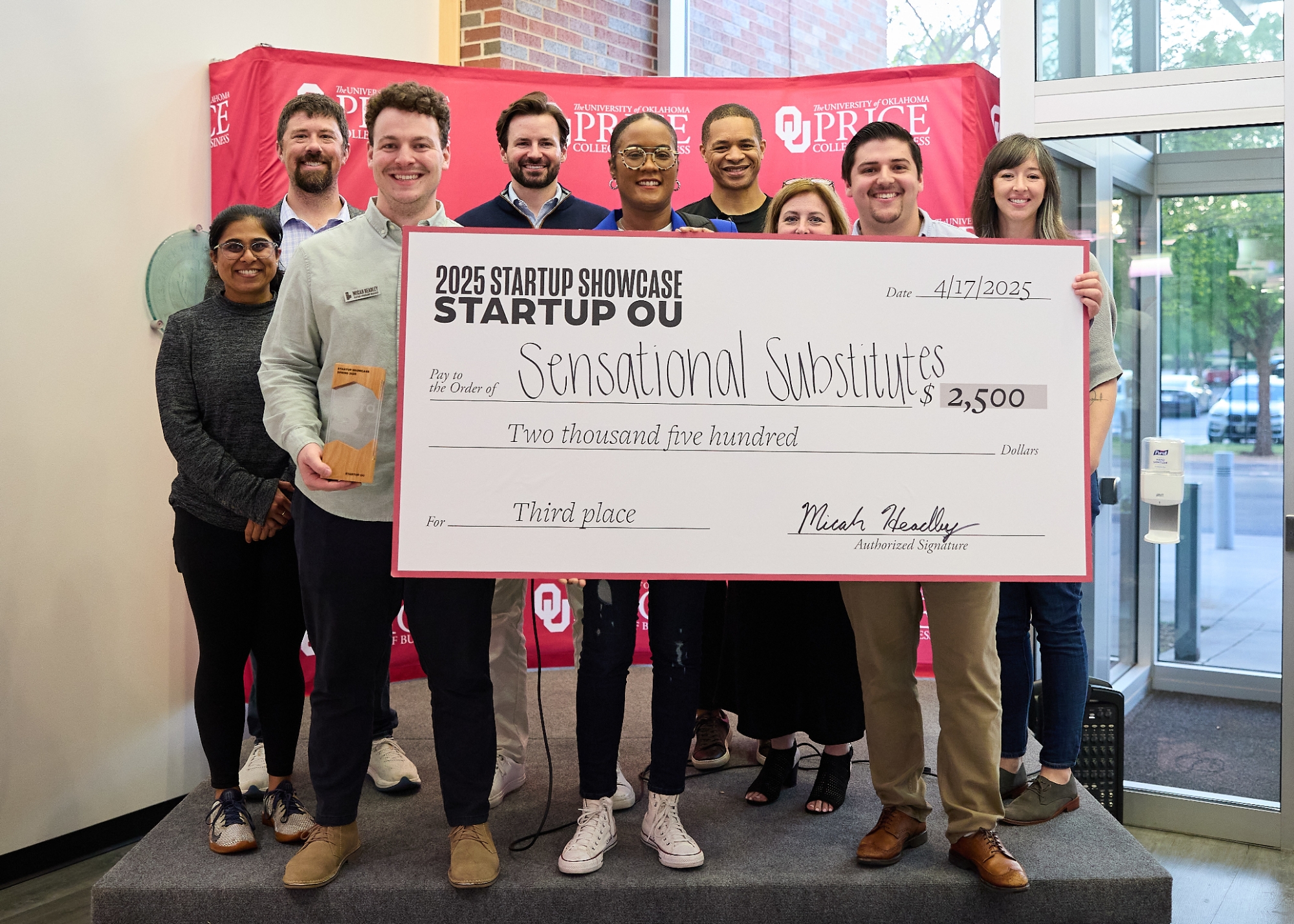 Founder holding a $2,500 award check from the Innovation Hub, standing with Innovation Hub staff.