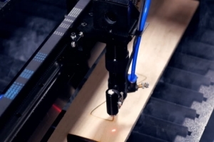 A laser cutter engraving a piece of wood.