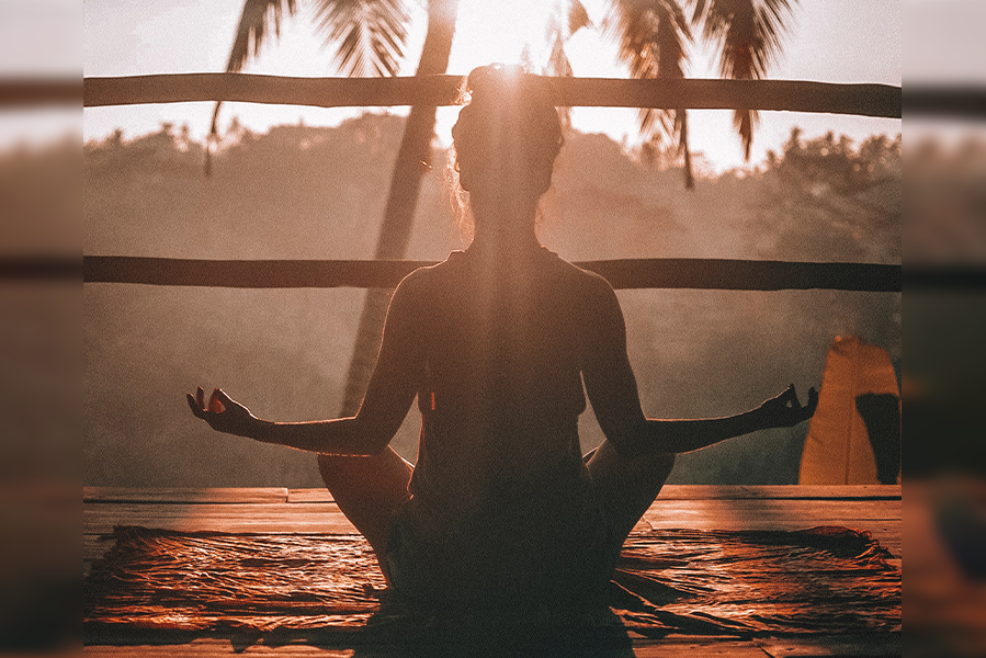 stock photo woman with back to the camera sits in full lotus pose at sunrise