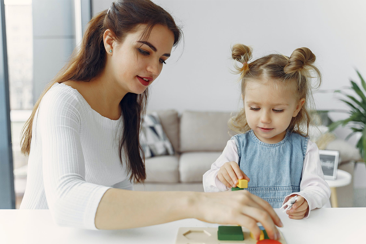 Stock Photo: woman and child stack blocks together at a table