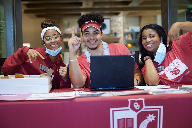 Three staff members pose at a check in table