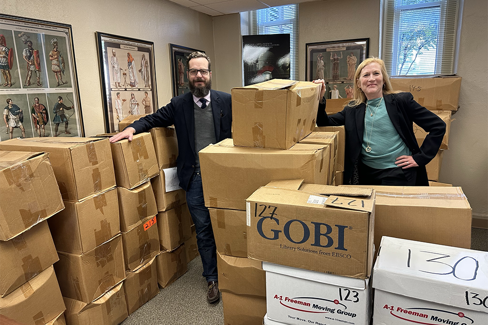 faculty pose with boxes of books in the Fears Library