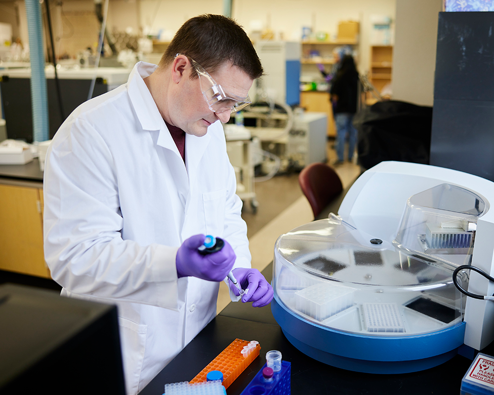 Klien, dressed in lab gear, prepares samples for testing