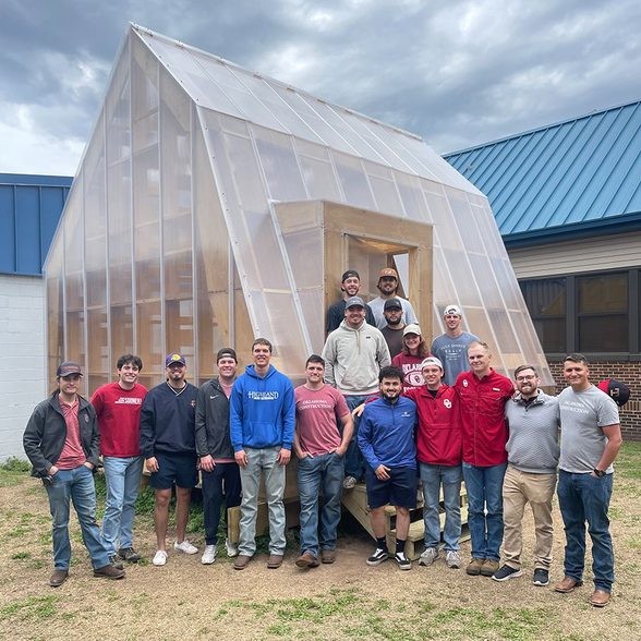 students pose in front of the greenhouse classroom
