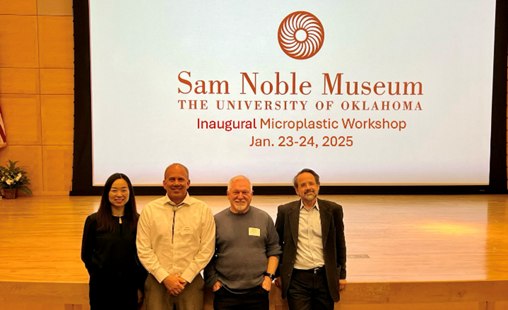 Four men standing in front of a presentation screen reading Sam Noble Museum Inaugural Microplastic Workshop