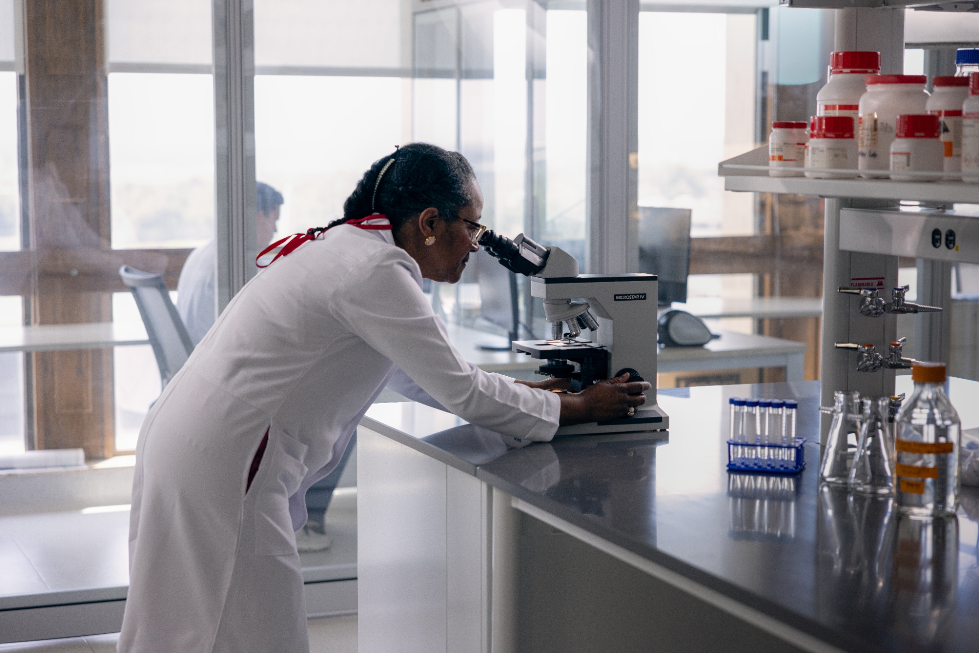 A researcher looking at a specimen using a microscope.