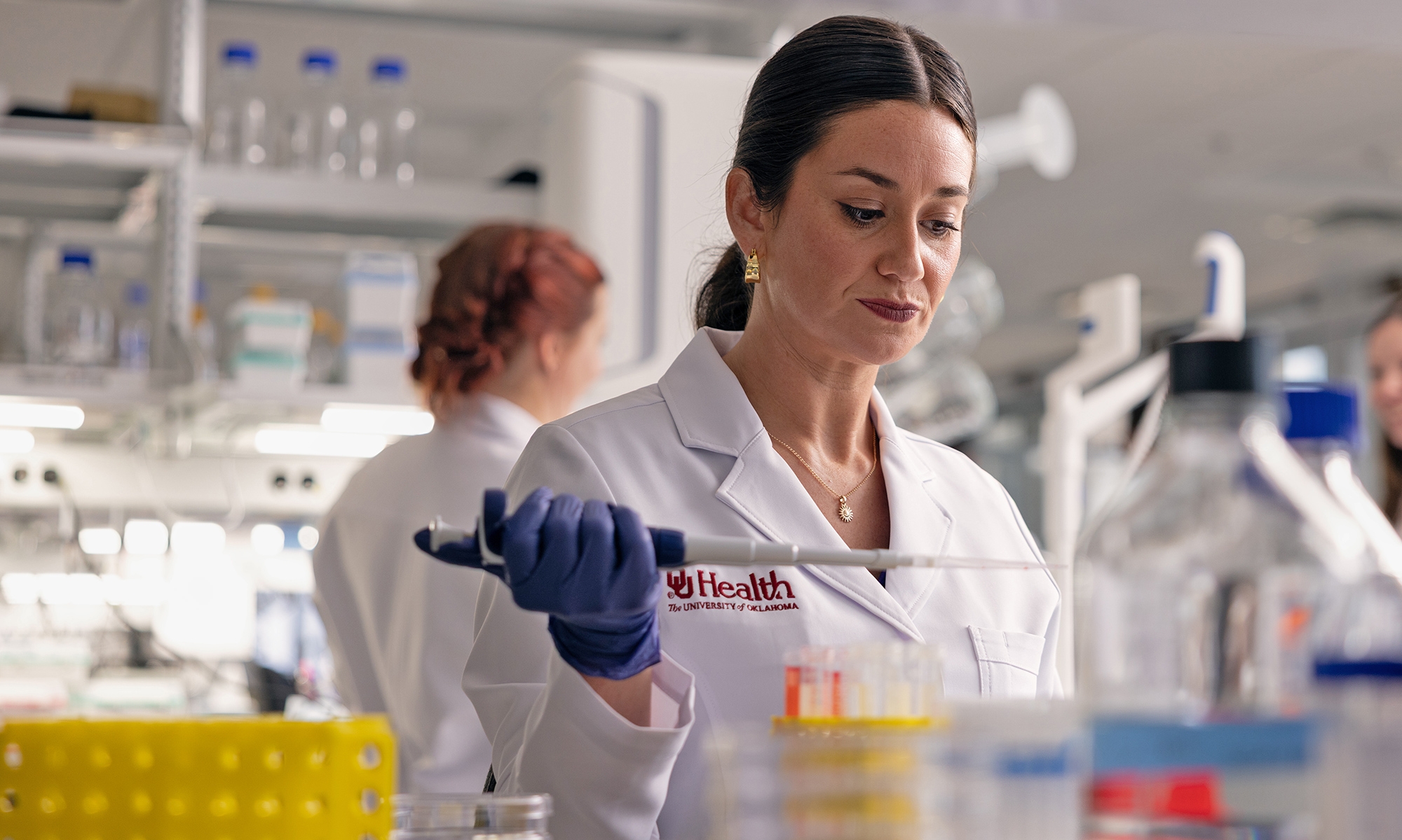 An OU Health researcher holding a pipette in a laboratory.