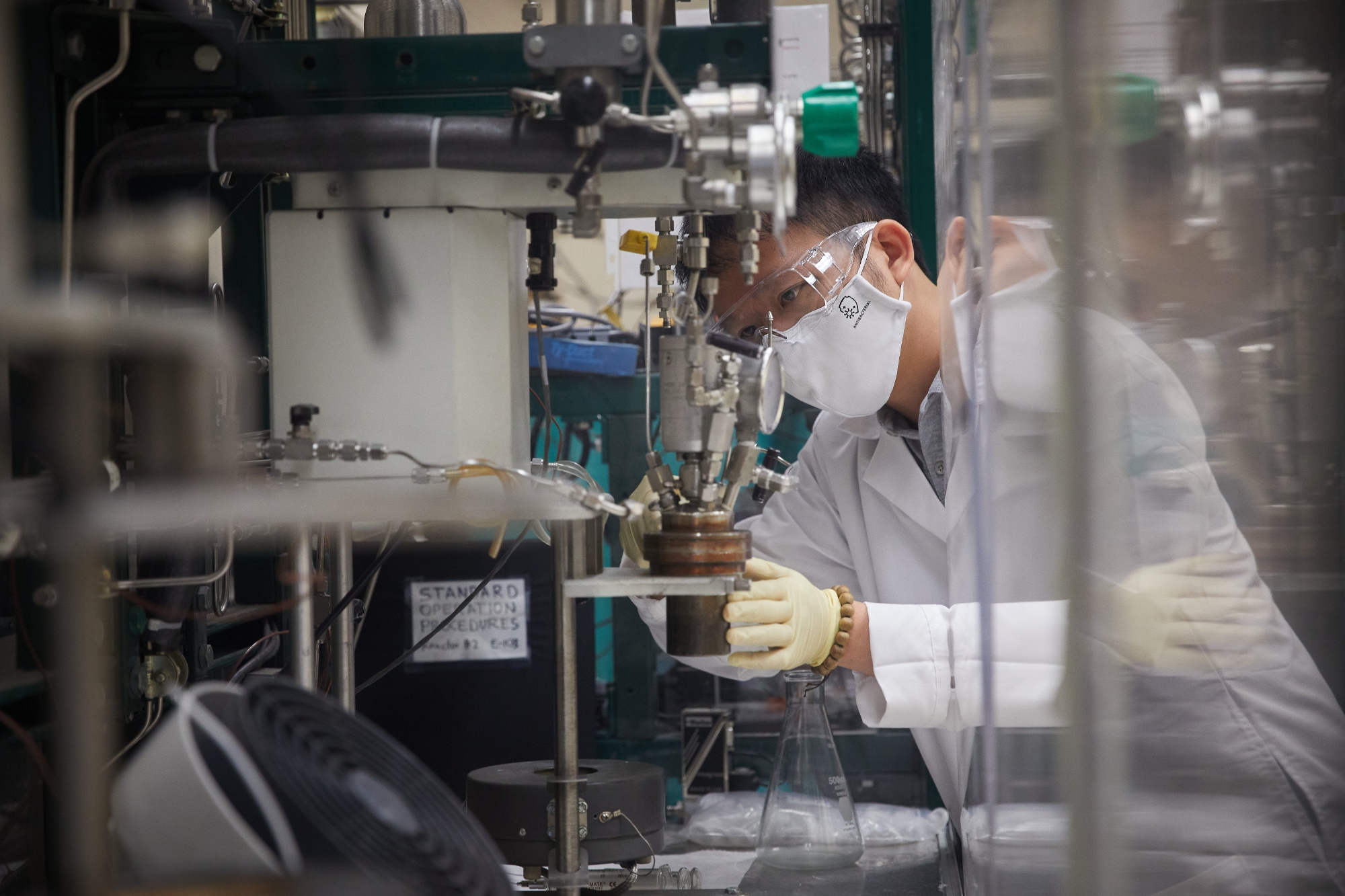 A person in protective gear, working in a laboratory.