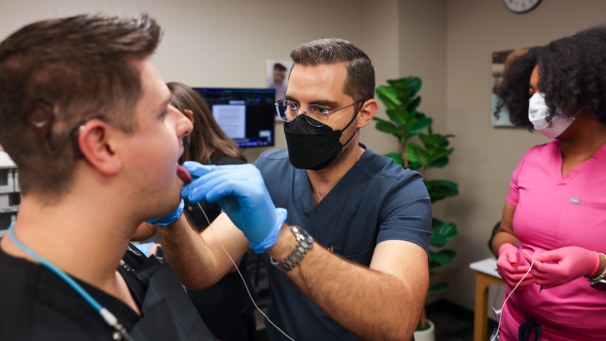 Two health professionals examining a patient's mouth.