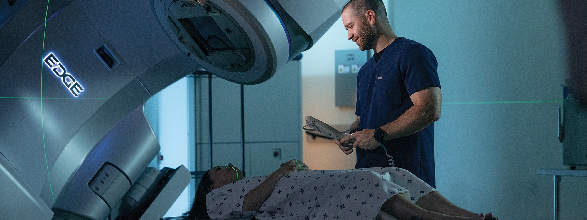 A medical technician speaking to a patient who is laying on a medical scanner.