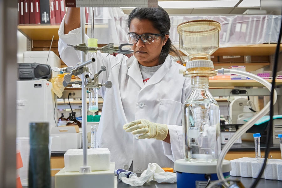 A person in laboratory gear working with instrumentation.