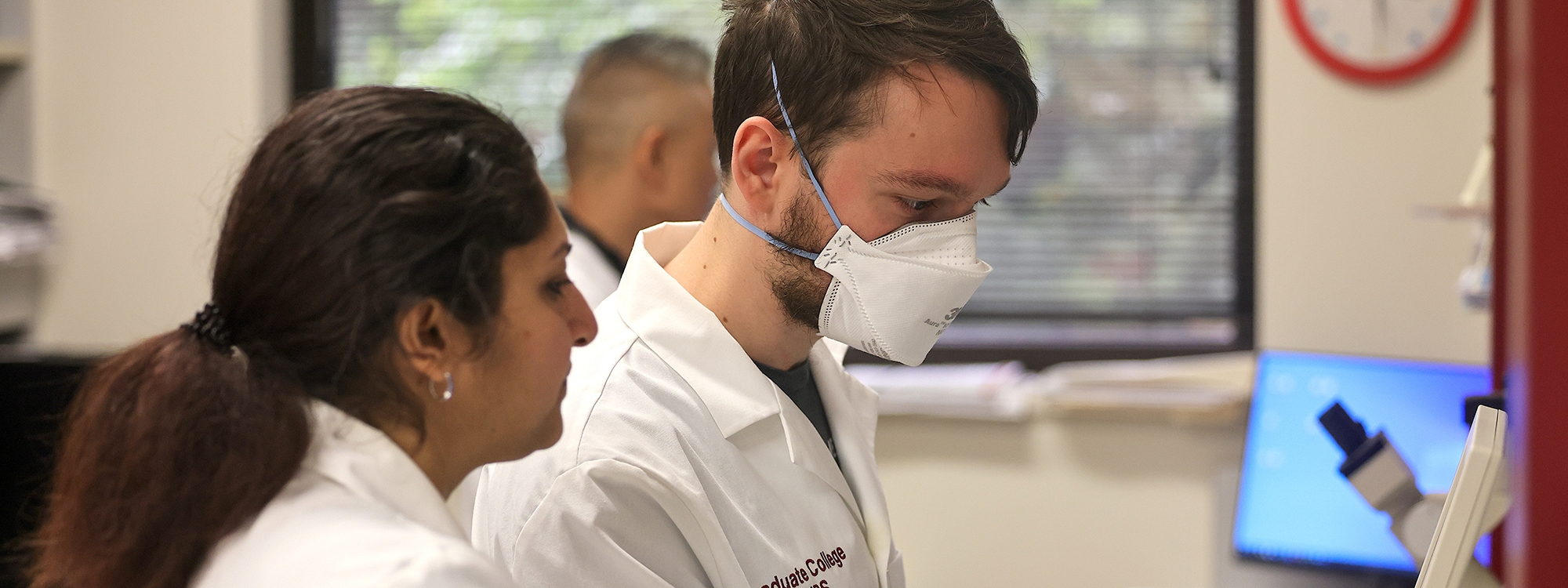 Researchers in white lab coats working with laboratory equipment.