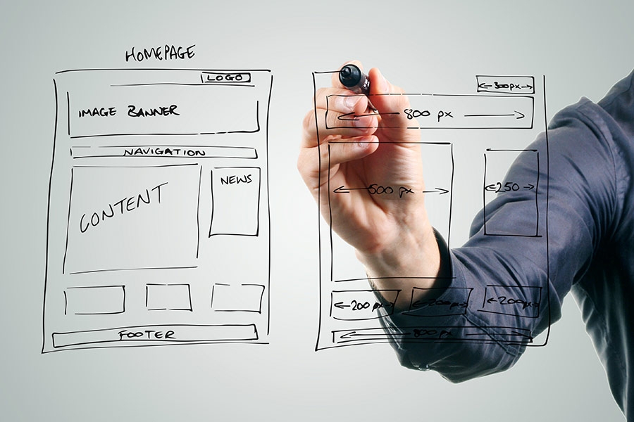 A person drawing some webpage layouts and mock ups on a white board.
