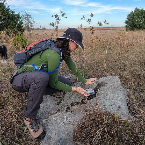 A student using a compass on a rock.