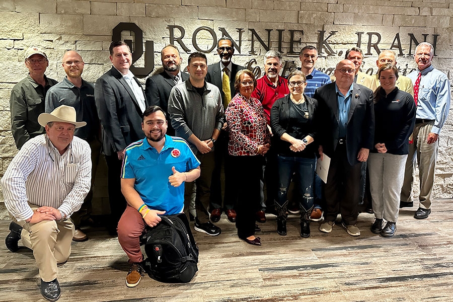 A group of alumni posing in front of a stone wall.