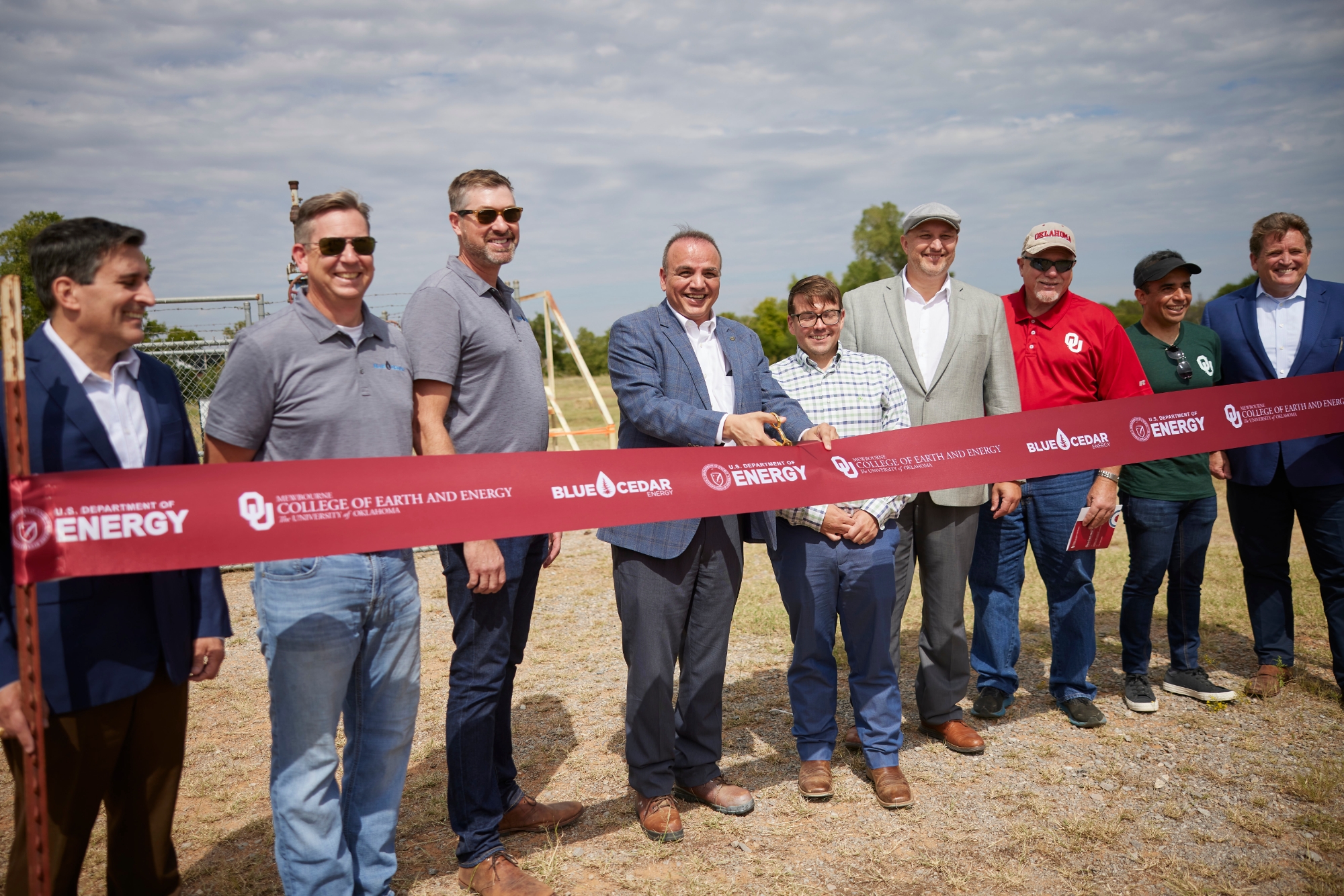 Project stakeholders and university leadership cut the ceremonial ribbon in front of a future geothermal well.