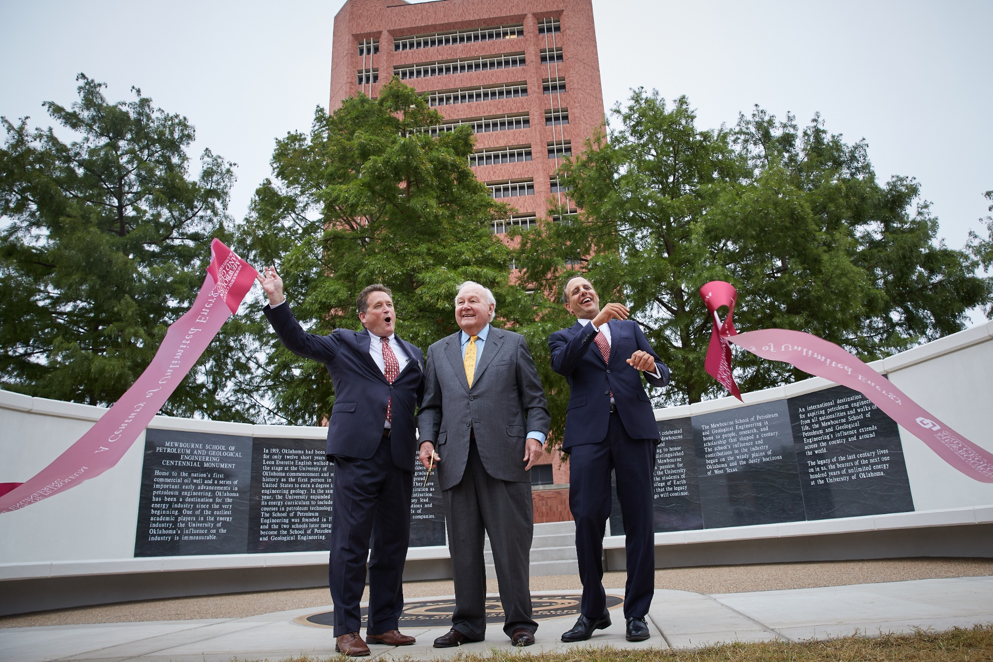 Dean J. Mike Stice, Curtis Mewbourne and President Joseph Harroz Jr. cut the ribbon to MPGE's Centennial monument in front of Sarkeys Energy Center. 