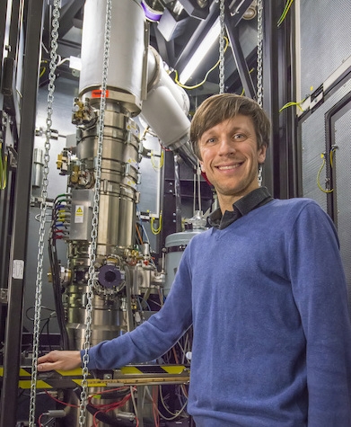 Image of Dr. Peter Ercius at Lawrence Berkeley National Laboratory standing with a transmission electron microscope