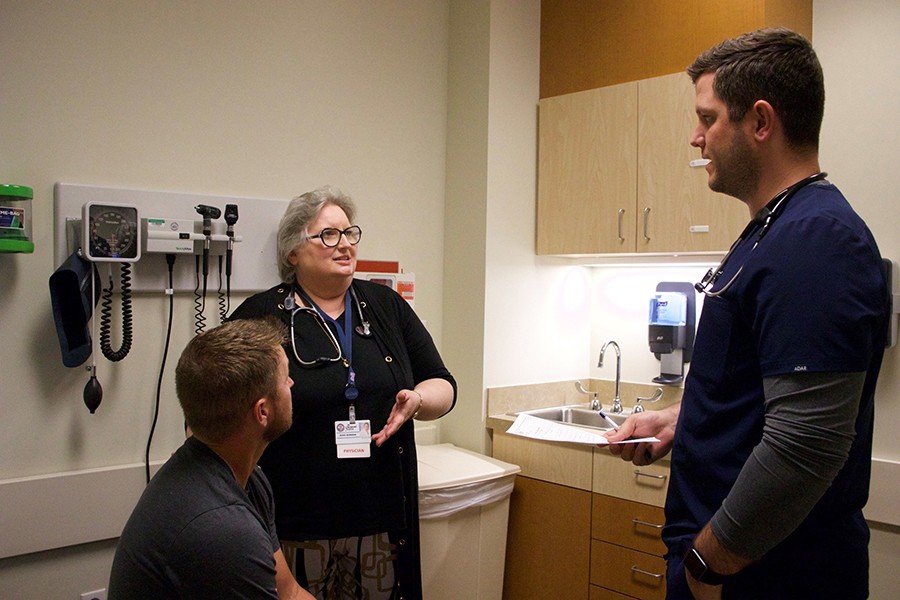 Chickasaw Nation Medical Center preceptor Rikki Scoggin, M.D., left, and OU College of Medicine student Wade McLanahan, right, visit with a patient.