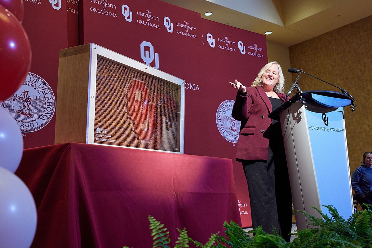 K20 Center Managing Director Leslie Williams discusses a work composed of 8,258 colored pencils arranged to create the interlocking OU logo to represent the number of students expected to benefit from the GEAR UP for LIFE program. 