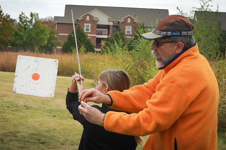Archery lesson with an instructor and child in a field near Sam Noble Museum.