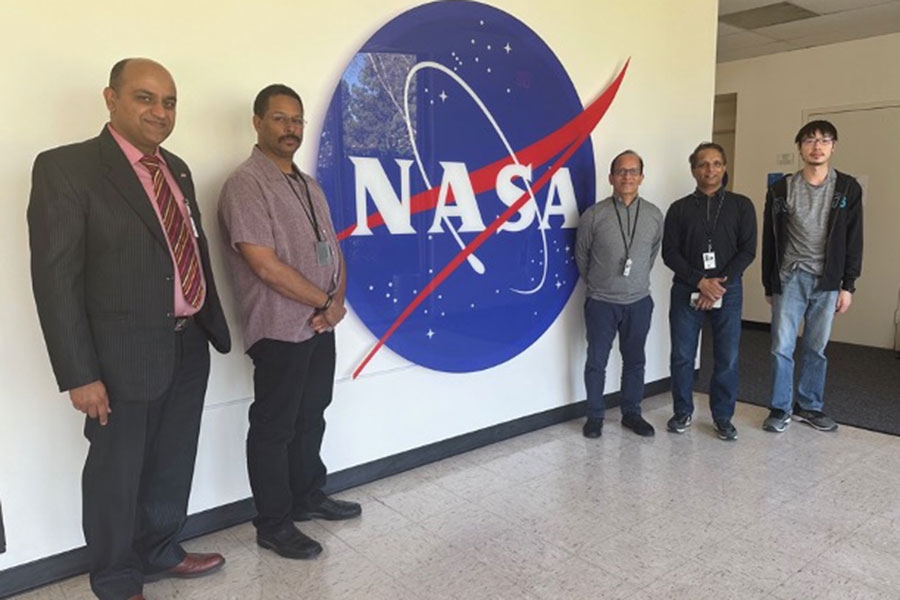 The research team stands in front of a wall displaying the NASA logo.
