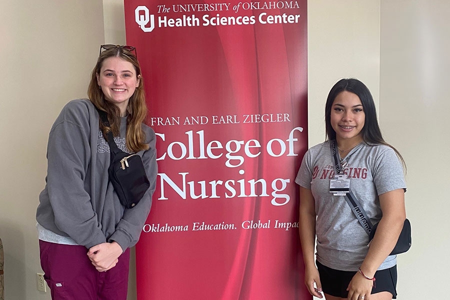 Two students standing in front of a College of Nursing banner.